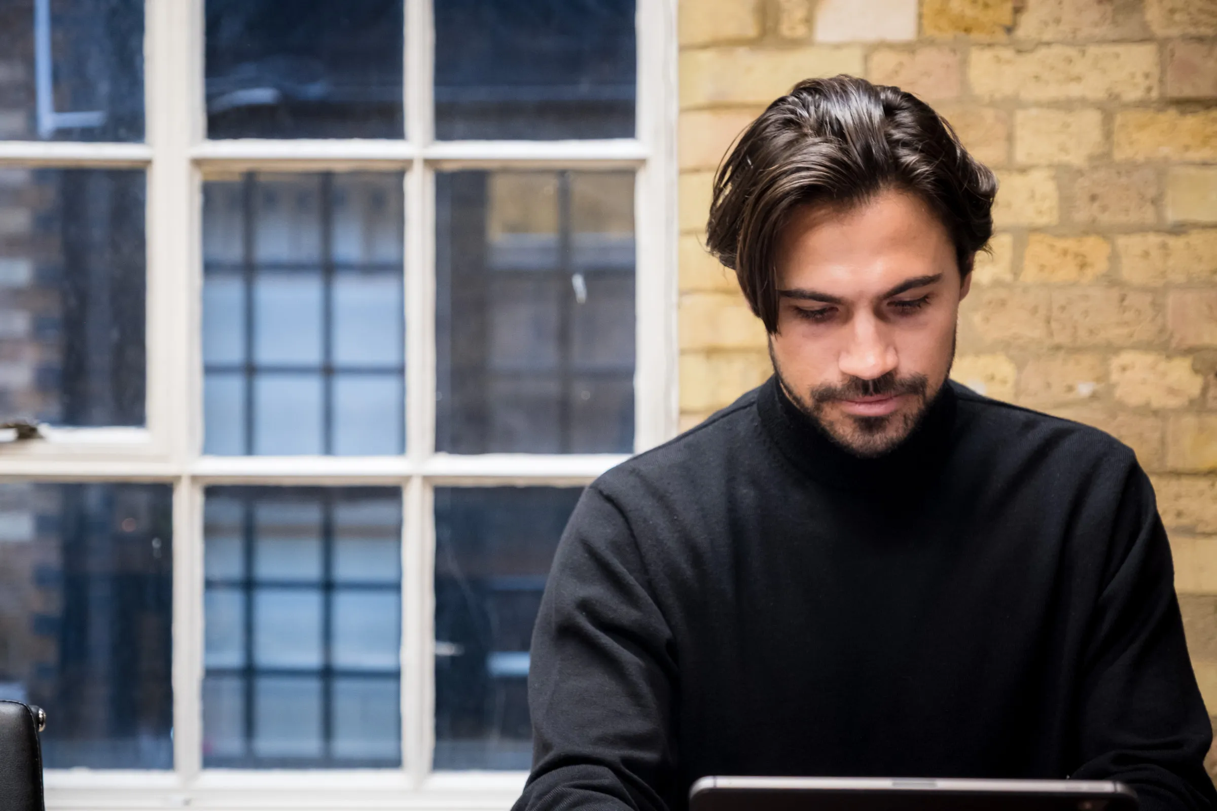 Backed VC - Founding partner working at a laptop, natural window light