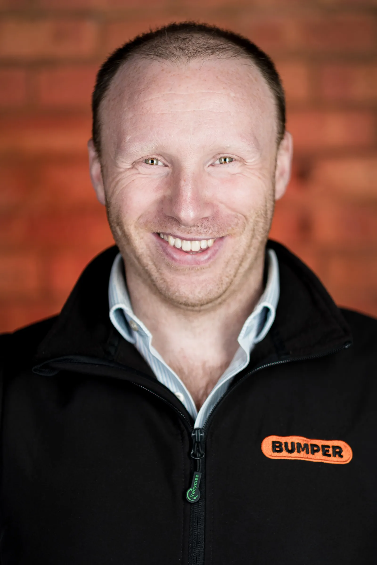 Bumper Team Photography - Individual headshot, branded Bumper gilet, exposed brick backdrop