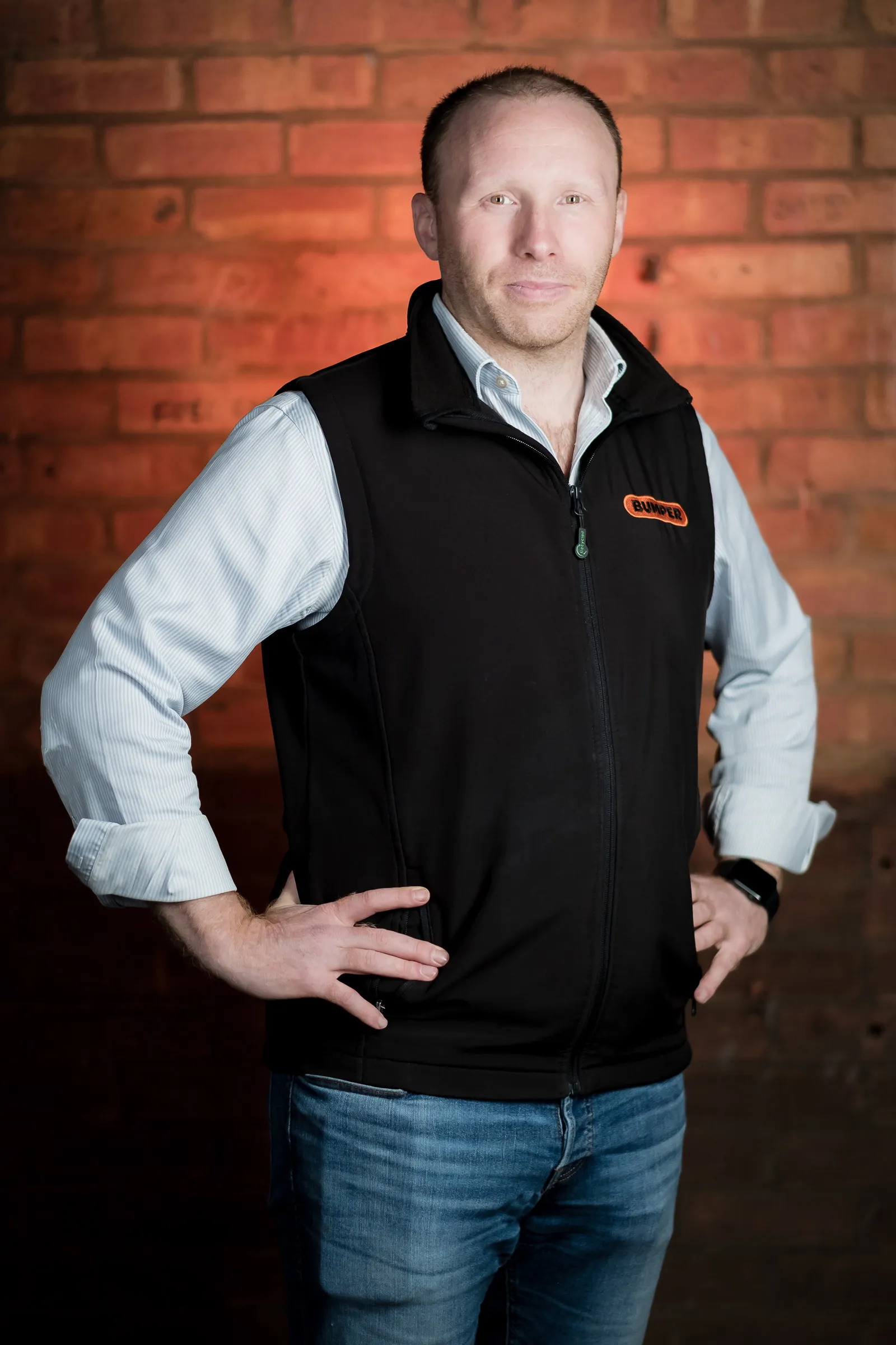 Bumper Team Photography - Three-quarter portrait, branded Bumper gilet, exposed brick backdrop