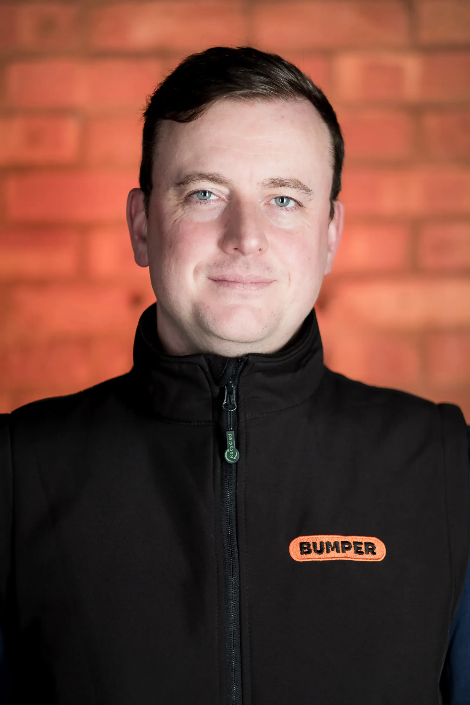 Bumper Team Photography - Individual headshot, branded Bumper gilet, exposed brick backdrop
