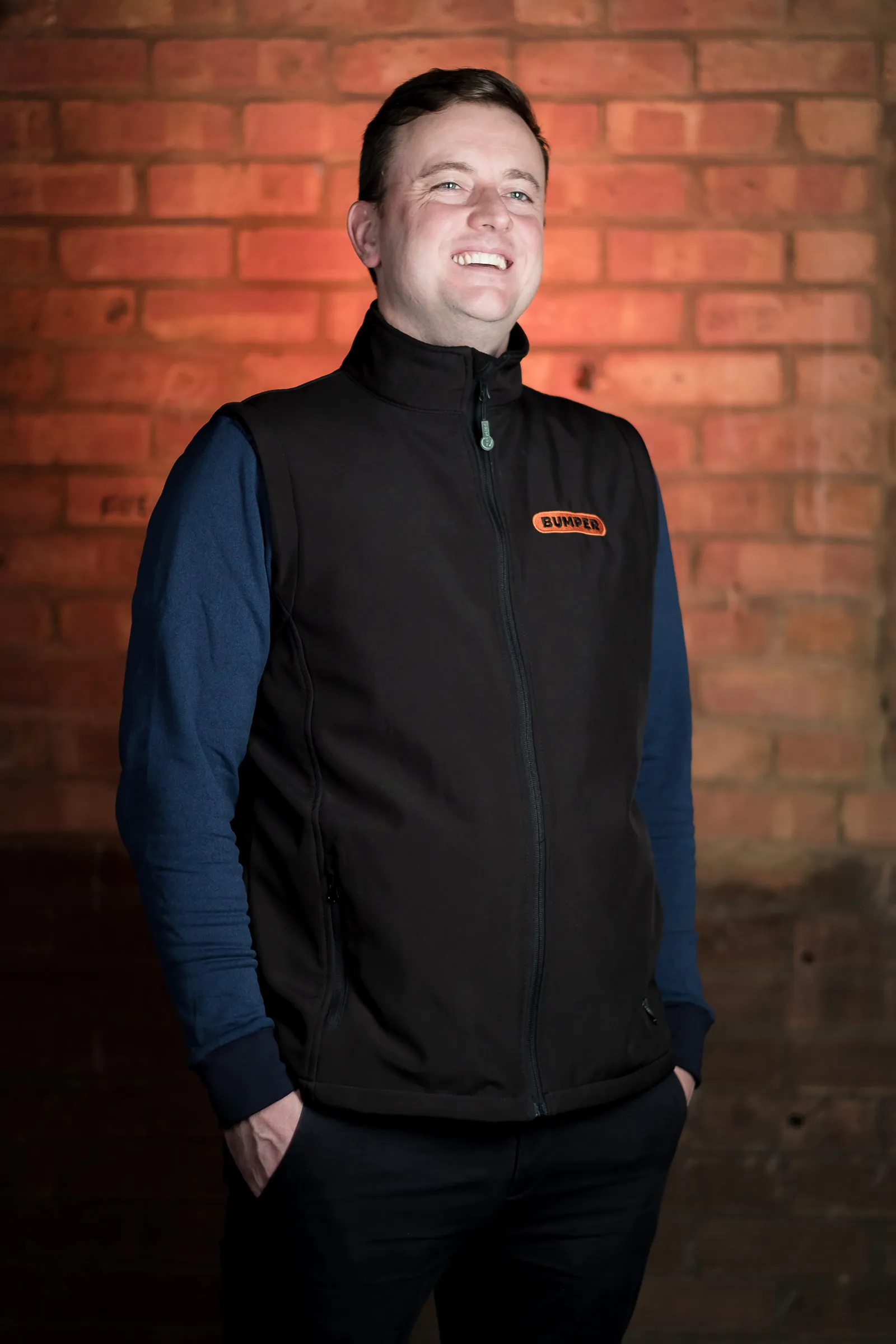 Bumper Team Photography - Three-quarter portrait, branded Bumper gilet, exposed brick backdrop