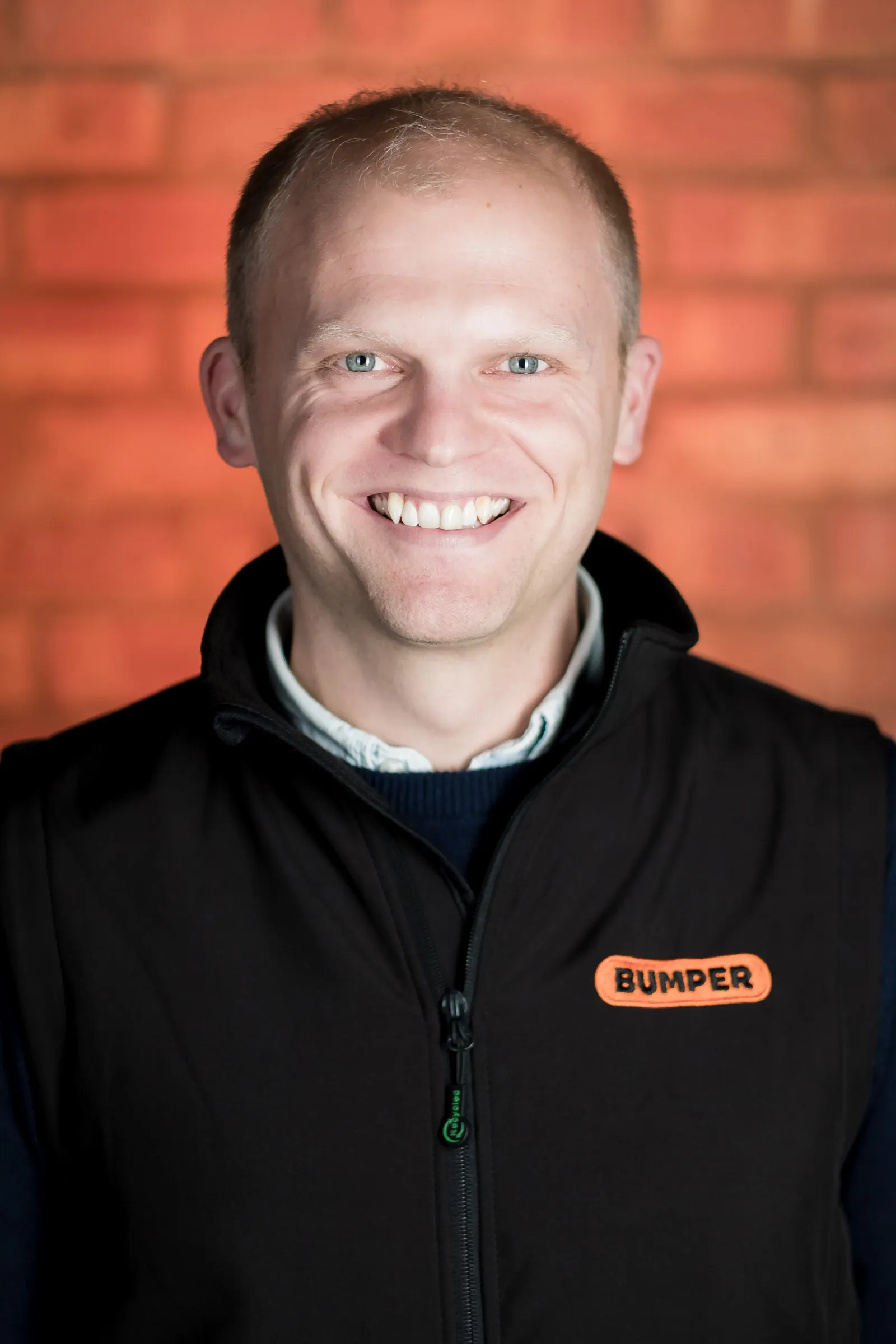 Bumper Team Photography - Individual headshot, branded Bumper gilet, exposed brick backdrop