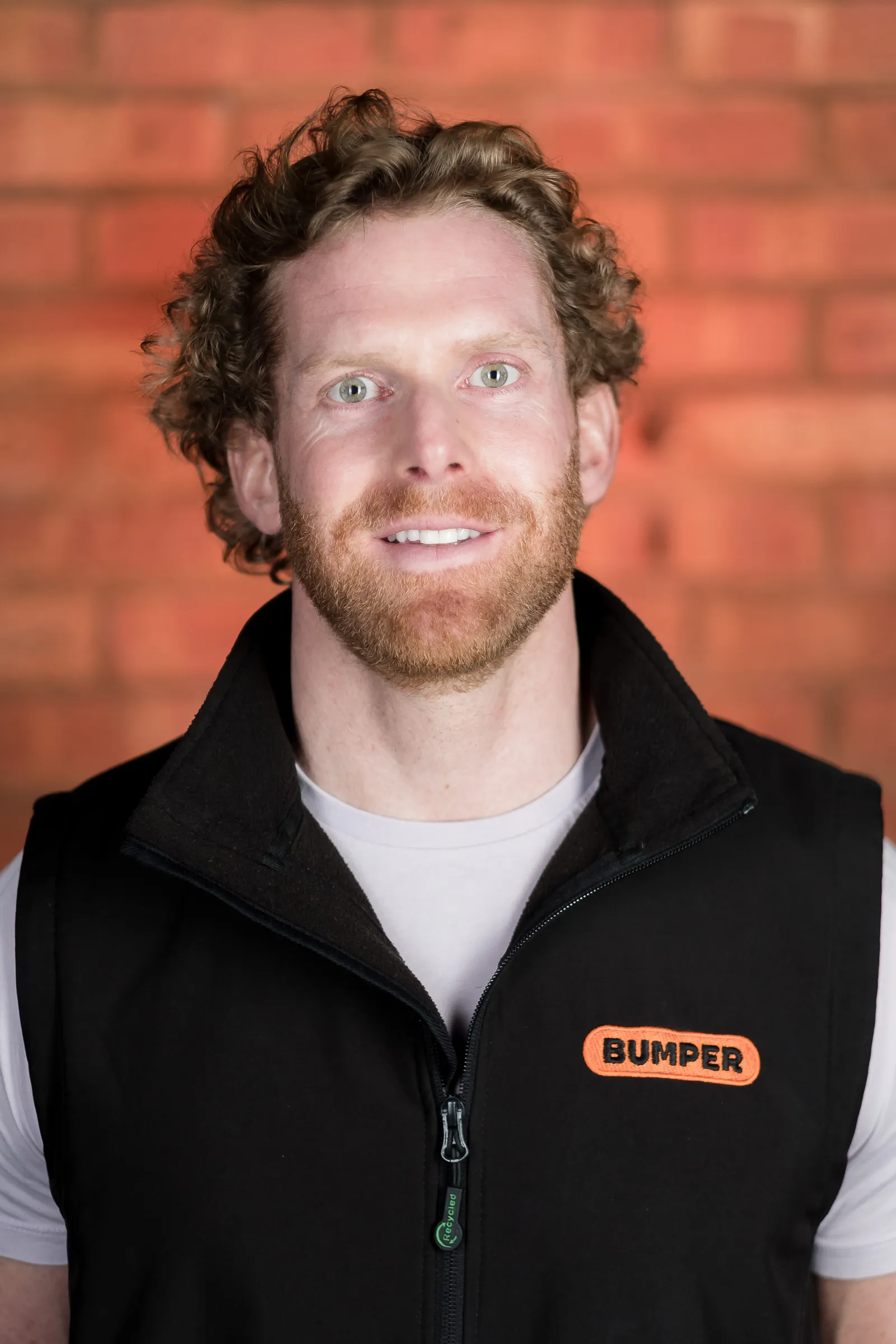 Bumper Team Photography - Individual headshot, branded Bumper gilet, exposed brick backdrop
