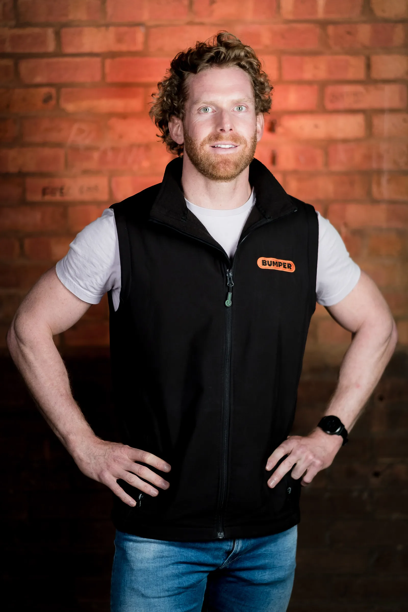 Bumper Team Photography - Three-quarter portrait, branded Bumper gilet, exposed brick backdrop