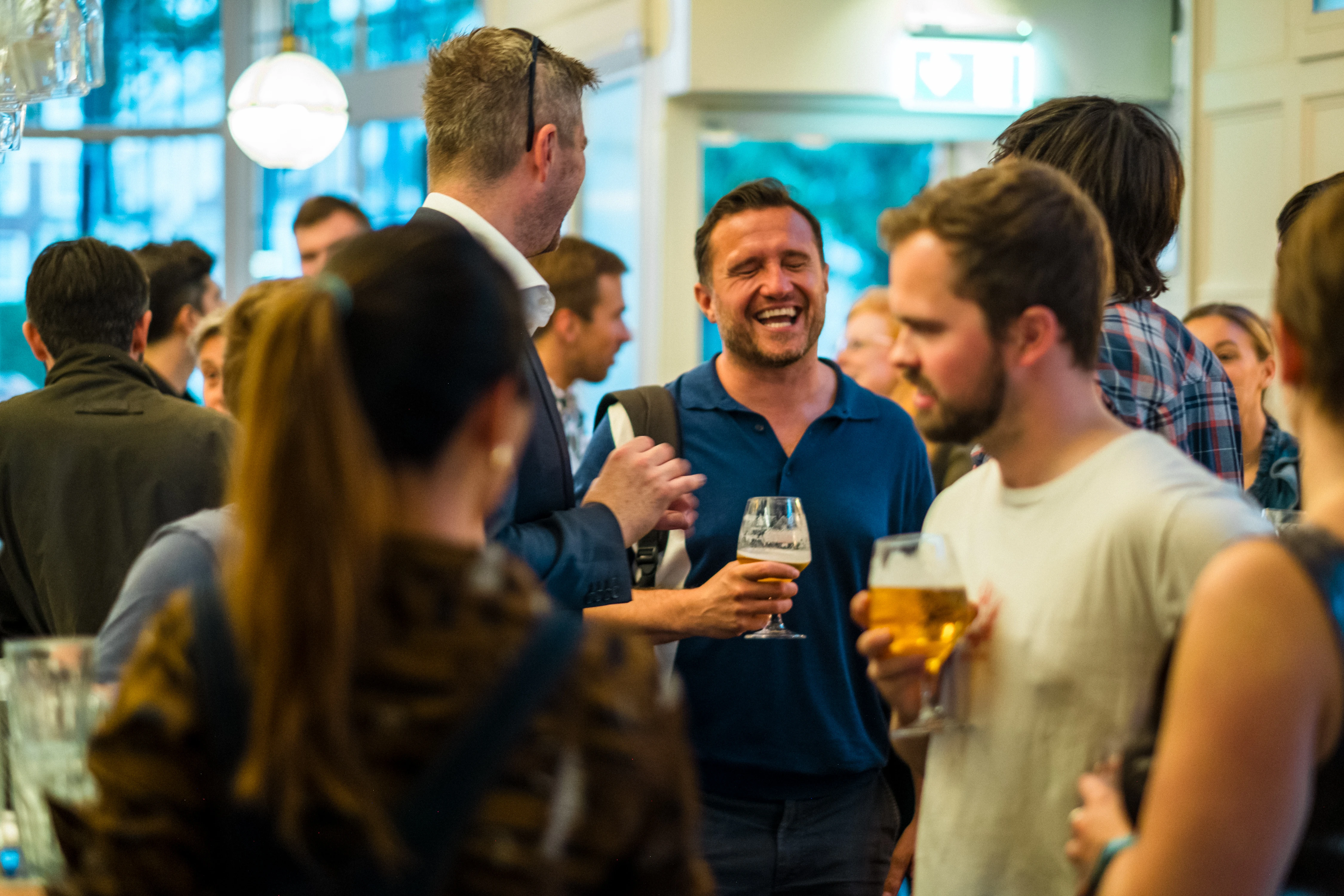 Planet A Ventures Meetup London - Mid-conversation laughter among a crowd holding pints